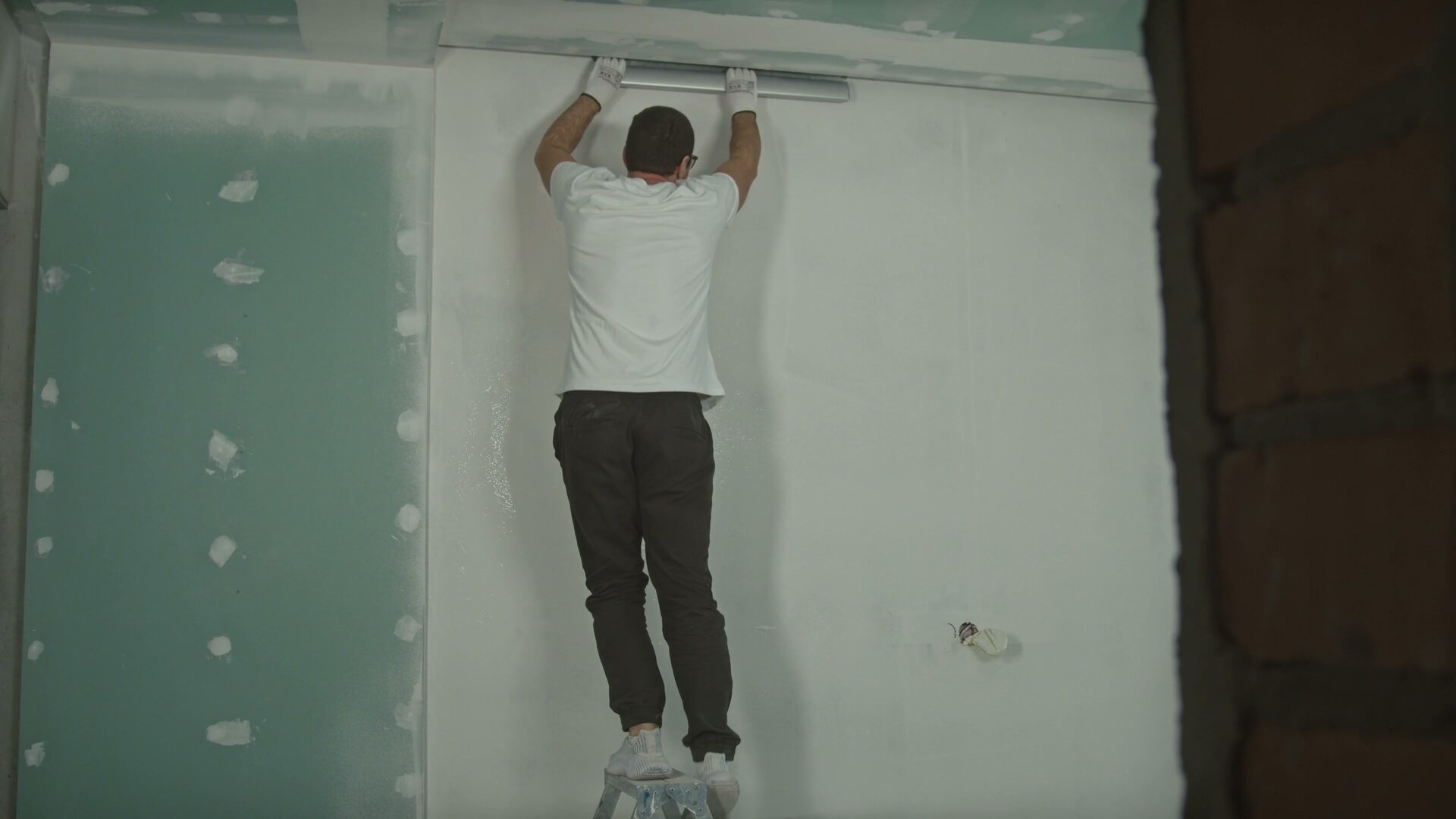 Artisan appliquant et lissant du plâtre sur un mur lors d'une rénovation intérieure résidentielle